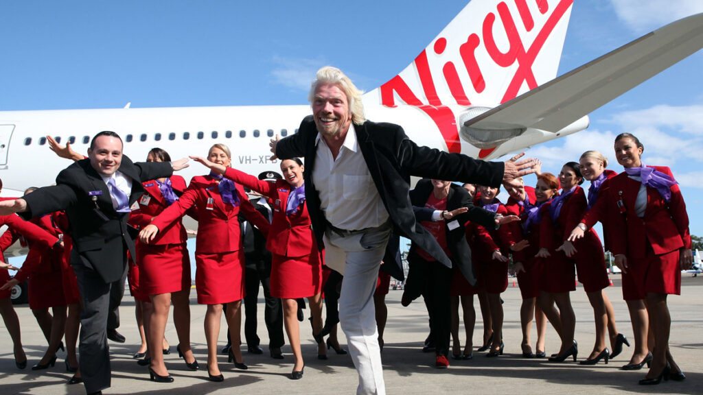 Richard Branson in front of Virgin Airlines crew and plane