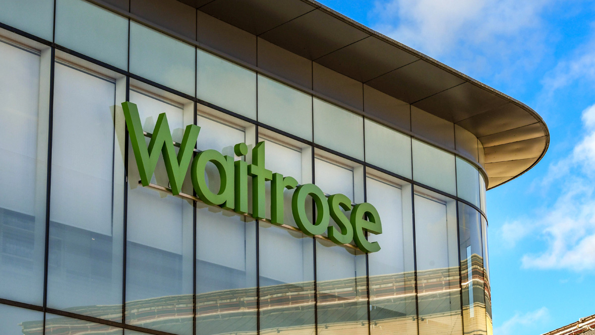 Large sign on the exterior glass panelled wall of a Waitrose supermarket in Windsor town centre