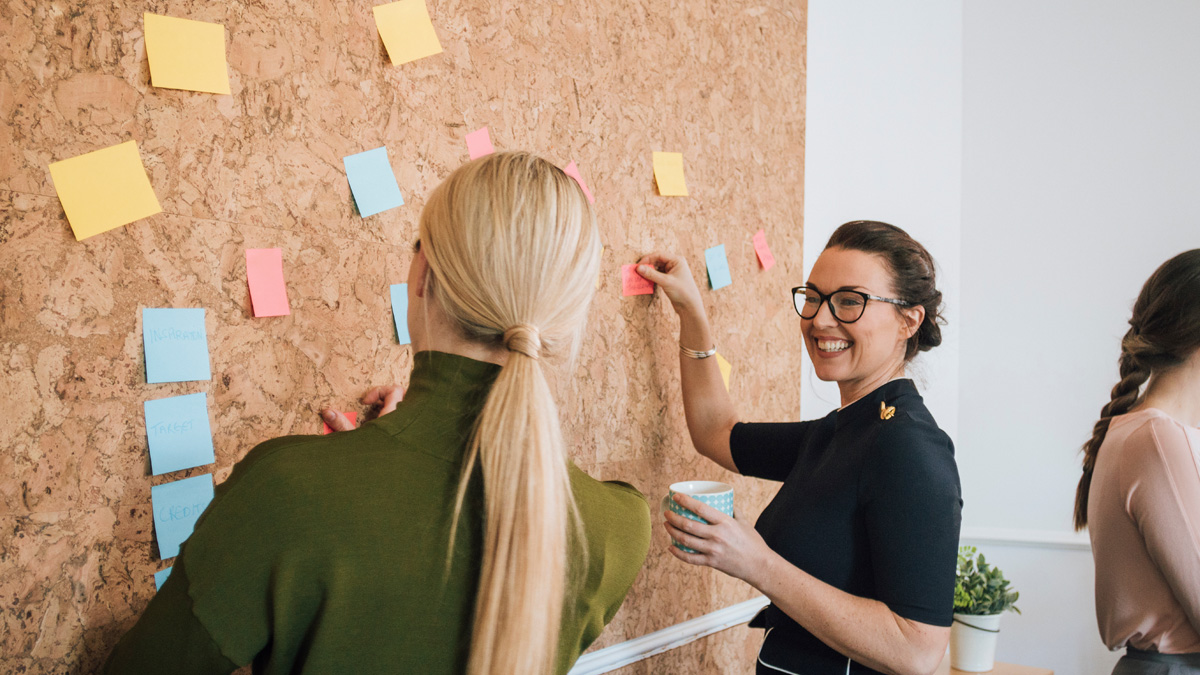 Two women using sticky notes to symbolise productivity