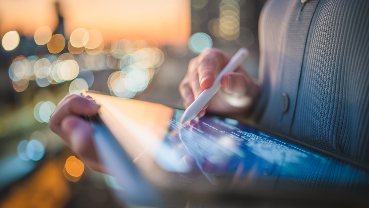 Person writing on a tablet with a cityscape in the background