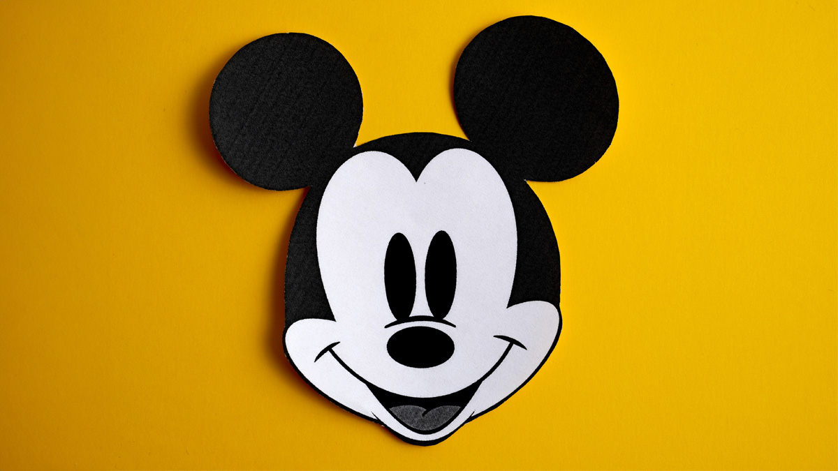 Black and white face of Mickey Mouse out of paper on a yellow background